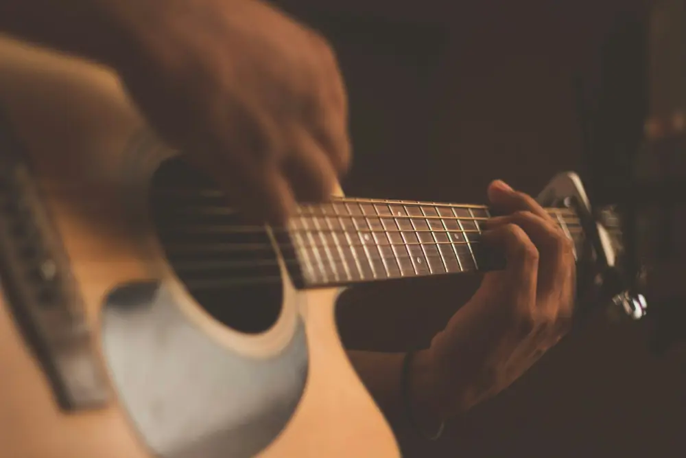 Mãos tocando violão numa noite de música