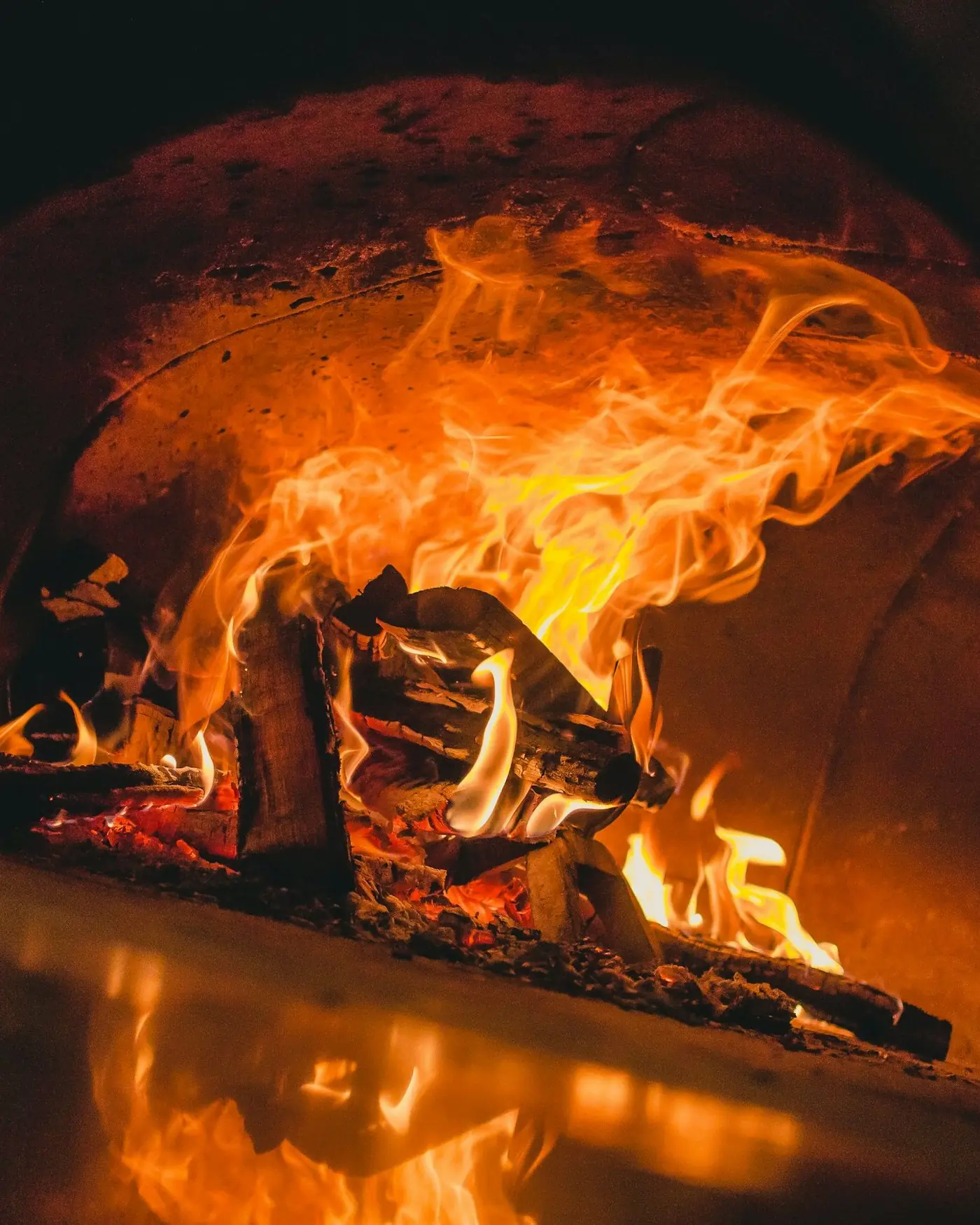 A boca do forno a lenha, com a lenha em chamas