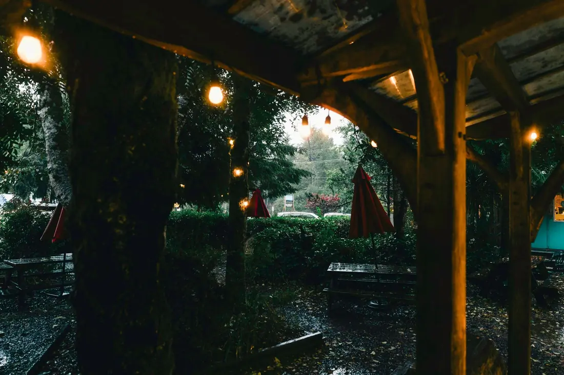 Pérgola de madeira com luzes penduradas sobre as mesas do quintal